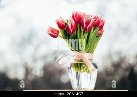 Un bouquet de tulipes roses fraîches dans un vase en verre à l'extérieur. Bouquet de fleurs Banque D'Images