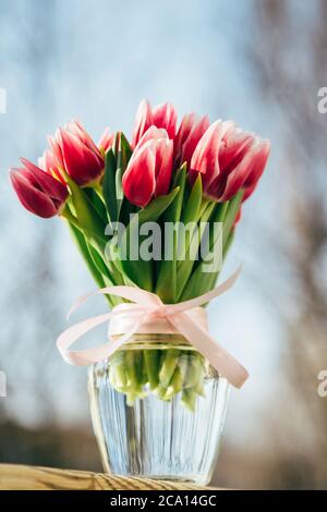 Un bouquet de tulipes roses fraîches dans un vase en verre à l'extérieur. Bouquet de fleurs Banque D'Images