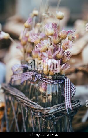 Petit bouquet de fleurs sauvages sèches immortelle en violet, rose dans de petits vases en verre à l'extérieur. Bouquet de fleurs Banque D'Images