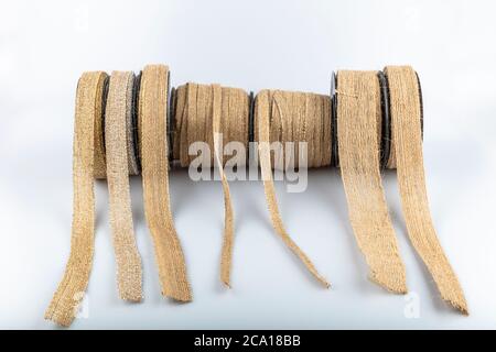 Rouleaux de ruban jute de couleur isolés sur fond blanc. Rouleau de ruban en lin vintage tressé naturel de corde de chanvre, ruban en lin pour papier cadeau. Banque D'Images