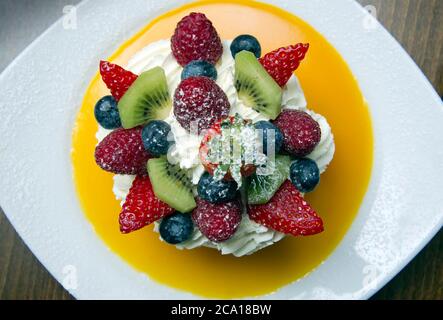 Fruits mélangés avec meringue, crème et coulis d'orange Banque D'Images