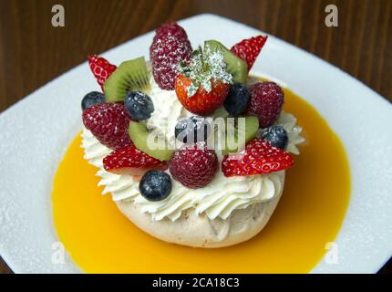 Fruits mélangés avec meringue, crème et coulis d'orange Banque D'Images