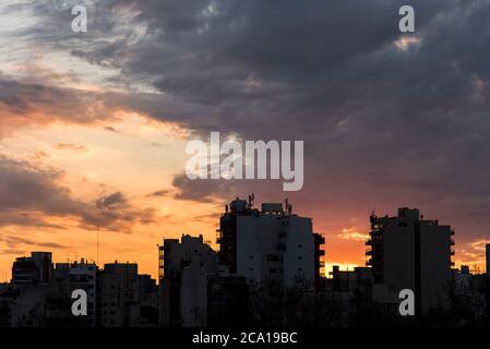 Coucher de soleil à Buenos Aires, Argentine. La silhouette de certains bâtiments en contre-jour contraste avec un ciel orange et nuageux Banque D'Images