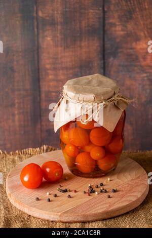 Tomates marinées dans un pot en verre sur fond de bois. Aliments fermentés tendance. Style rustique. Banque D'Images