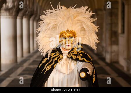 VENISE, ITALIE - 28 JANVIER 2018 : une personne avec une robe de costume typique noir, blanc et or et un masque facial or pendant le carnaval de Venise Banque D'Images