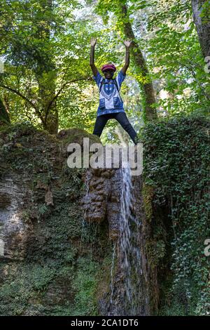 Une femme africaine se tient heureuse au sommet d'une cascade lors d'une journée chaude en été. La cascade de Linner est la plus grande cascade du canton d'Argau, située à Banque D'Images