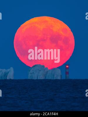 Mudeford, Dorset, Royaume-Uni. 3 août 2020. Météo Royaume-Uni. La pleine lune d'esturgeon brille de rouge alors qu'elle s'élève de derrière le phare d'aiguilles sur l'île de Wight, vue depuis Mudeford Quay à Dorset, lors d'une soirée d'été claire. Crédit photo : Graham Hunt/Alamy Live News Banque D'Images