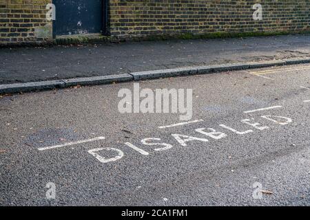 Mot DÉSACTIVÉ écrit sur l'asphalte près de l'espace de stationnement réservé dans la rue dans le quartier de Londres Banque D'Images