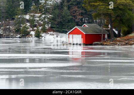 Lac Rosseau avec des serres le long de la rive pendant un dégel hivernal, ruisseau (Ontario), Canada Banque D'Images
