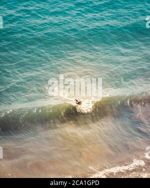 Vue descendante d'un surfeur solitaire qui tente de prendre une petite vague dans l'océan Pacifique près de Santa Barbara, CA, USA Banque D'Images