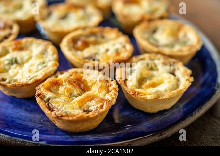 Gastronomie brésilienne. Tartes au fromage et à la viande séchées avec des arugula dans un plat fait à la main sur une table en bois. Banque D'Images