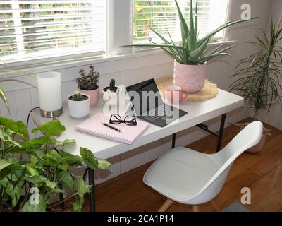 table dans pièce intérieure blanche bureau avec ordinateur portable et plantes en pot et chaise blanche Banque D'Images