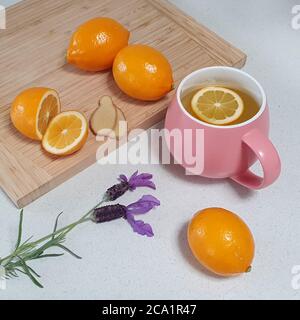 thé sain au citron et au gingembre chaud dans une tasse rose avec citrons frais Banque D'Images