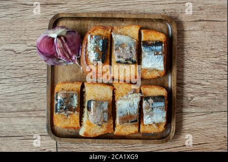 photo de croûtons à l'ail râpé avec des morceaux de poisson sur un plaque carrée en bois Banque D'Images