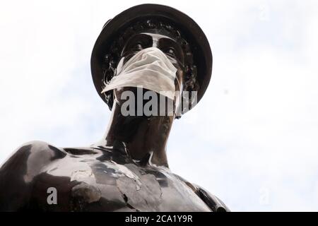 La statue de la Mercurial dans la rue Glasgow a été transformée en symbole du coronavirus (Covid 19) en portant un masque protecteur. Banque D'Images