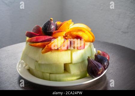 Assiette de fruits, melon, pêches et figues sur la table. Délicieux et délicieux fruits frais dans une assiette blanche Banque D'Images