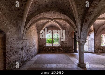 Intérieur de la salle d'un ancien monastère médiéval, avec une voûte en croix gothique et deux fenêtres à meneaux Banque D'Images