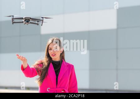 des terrains de drone sur la main, jeune femme défoqué en arrière-plan, se concentrent sur le quadricoptère Banque D'Images