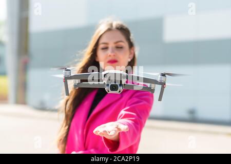 des terrains de drone sur la main, jeune femme défoqué en arrière-plan, se concentrent sur le quadricoptère Banque D'Images