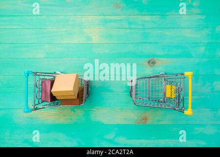 Panier rempli de boîtes et vide un autre sur fond de bois bleu vintage. Deux petits chariots - vides et avec des boîtes. Vue de dessus, Copy spa Banque D'Images