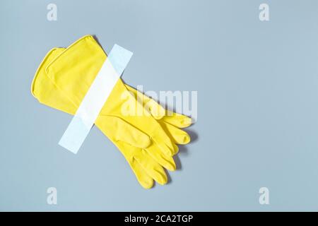 Gants jaunes collés avec du ruban adhésif sur le mur. Paire de gants de protection pour le nettoyage isolé sur l'arrière-plan. Installation des accessoires couleur banane et du ruban adhésif Banque D'Images