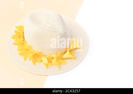 Chapeau de paille avec fleurs de nénuphars jaunes sur fond blanc et isolé. Modèle rétro élégant. Fond jaune. Conc. Mode été Banque D'Images