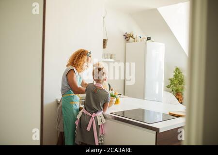 cuisine et concept de maison - vue arrière de famille heureux aimant préparant la boulangerie ensemble sur fond blanc de cuisine Banque D'Images