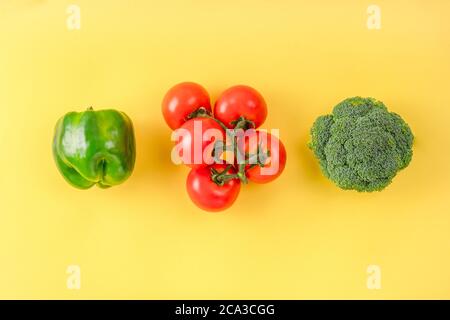 Composition à plat avec fruits et légumes frais sur fond de couleur. Brocoli, tomate, poivre sur surface jaune. Mise en page créative. Banque D'Images