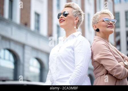 Deux dames en lunettes posant dehors office building Banque D'Images