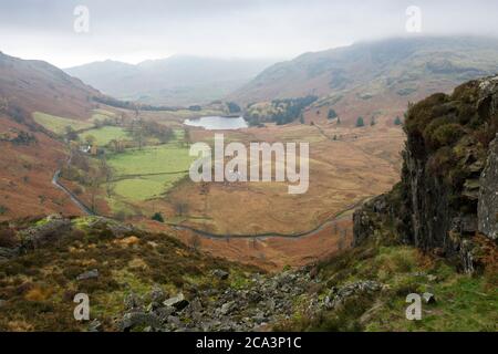 Blea Tarn dans la vallée entre Lingmoor est tombé et Wrynose est tombé de côté Pike avec Wetherlam dans les nuages au-delà. Lake District National Park, Cumbria, Angleterre. Banque D'Images