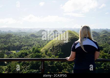 Femme blonde au point de vue à Bohol, aux Philippines, regardant la vue inspirante du célèbre paysage connu sous le nom de collines de chocolat Banque D'Images