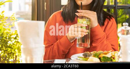 Femme buvant un cocktail avec un repas de poisson Banque D'Images