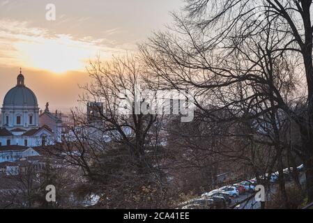 Architecture et nature italiennes : bois sans feuilles sur Colle Cidneo. Le dôme de Santa Maria Assunta (St. Mary) domine la ville au coucher du soleil Banque D'Images