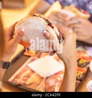 Femme tenant un hamburger, un âne Banque D'Images