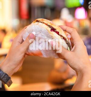 Femme tenant un hamburger, un âne Banque D'Images