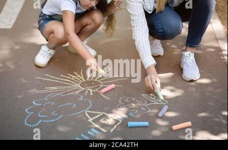 Mère et fille dessin avec craies de couleur dehors, Cropped Banque D'Images