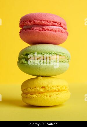 pile de macarons cuits sur fond jaune, délicieux dessert à base de farine d'amande, gros plan Banque D'Images