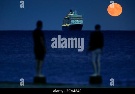 Bournemouth, Royaume-Uni. 3 août 2020. La pleine lune d'août, parfois connue sous le nom de Sturgeon Moon, s'élève derrière le navire de croisière Cunard Line Queen Elizabeth à l'ancre dans la baie Poole, au large de la plage de Bournemouth. Credit: Richard Crease/Alay Live News Banque D'Images