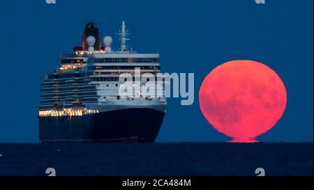 Bournemouth, Royaume-Uni. 3 août 2020. La pleine lune d'août, parfois connue sous le nom de Sturgeon Moon, s'élève derrière le navire de croisière Cunard Line Queen Elizabeth à l'ancre dans la baie Poole, au large de la plage de Bournemouth. Credit: Richard Crease/Alay Live News Banque D'Images