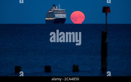 Bournemouth, Royaume-Uni. 3 août 2020. La pleine lune d'août, parfois connue sous le nom de Sturgeon Moon, s'élève derrière le navire de croisière Cunard Line Queen Elizabeth à l'ancre dans la baie Poole, au large de la plage de Bournemouth. Credit: Richard Crease/Alay Live News Banque D'Images