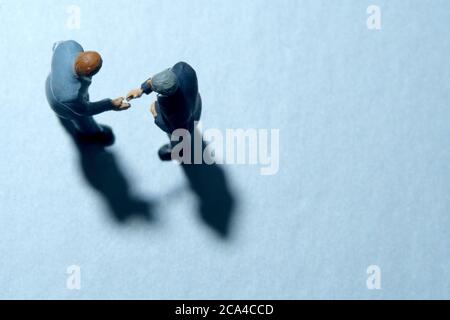 Vue de dessus de deux hommes d'affaires font un accord de partenariat poignée de main. Les personnes miniatures se font une photographie conceptuelle Banque D'Images