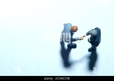 Vue de dessus de deux hommes d'affaires font un accord de partenariat poignée de main. Les personnes miniatures se font une photographie conceptuelle Banque D'Images