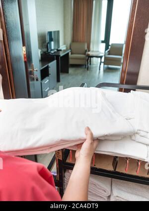 Service d'étage de l'hôtel, femme emportant une serviette dans la chambre Banque D'Images