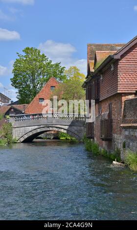 Rivière Itchen traversant Winchester le long d'un bâtiment médiéval avec le pont de la ville en arrière-plan. Banque D'Images