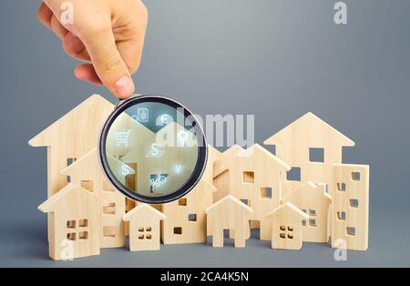 Realtor examine les maisons à travers une loupe. Examen du marché immobilier, recherche des meilleures offres basées sur les critères de prix, locat Banque D'Images