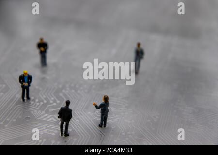 Figurines miniatures posées en tant que gens d'affaires dans une réunion sur le circuit imprimé futuriste abstrait, futur concept d'affaires Banque D'Images