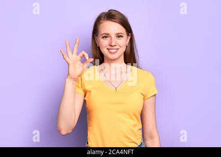 Photo de jeune femme gaie attrayante fait un geste correct, démontre l'accord et que tout est bien, a une humeur impressionnante, des émotions positives. Banque D'Images