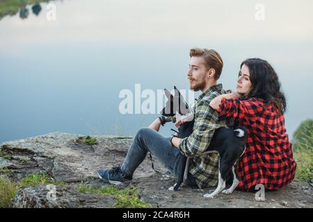 jeune couple et leur adorable chien regardant la distance, gros plan vue de côté photo. espace de copie, temps libre, temps libre, détente, loisirs Banque D'Images