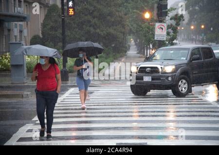 Washington, États-Unis. 04e août 2020. Des piétons marchent sous la pluie pendant la tempête tropicale Isaías à Washington, DC, le 4 août 2020 dans le contexte de la pandémie du coronavirus. La tempête a été rétrogradée d'un ouragan après avoir fait une chute en Caroline du Nord la nuit dernière, pendant que les négociations se poursuivent entre le Congrès et la Maison Blanche sur un plan de relance supplémentaire de la COVID-19 avec les Démocrates unis et les Républicains qui continuent à établir un consensus au sein de leurs rangs. (Graeme Sloan/Sipa USA) Credit: SIPA USA/Alay Live News Banque D'Images