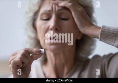 La femme mature toucher le front souffre de maux de tête tenant la drogue analgésique Banque D'Images